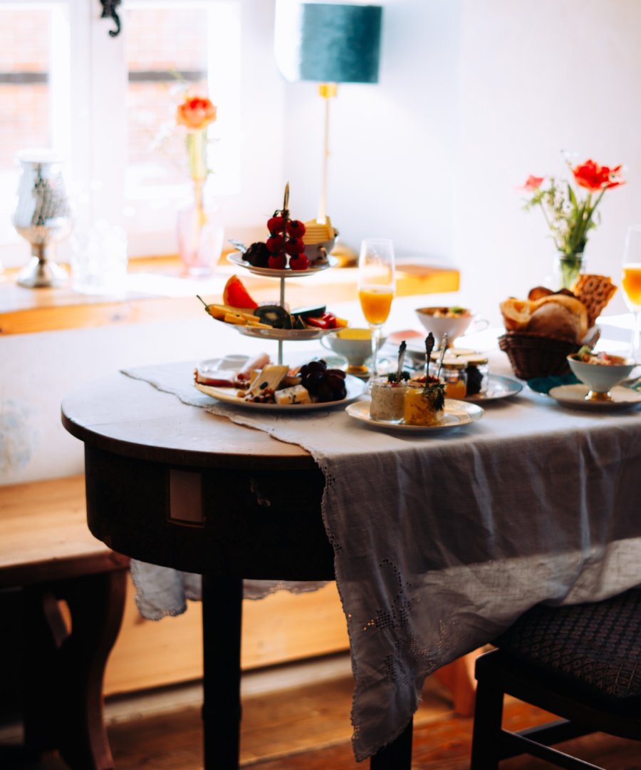 Ontbijtruimte in een hotel met linnen tafellinnen en gebloemd servies, door cestsjoukje