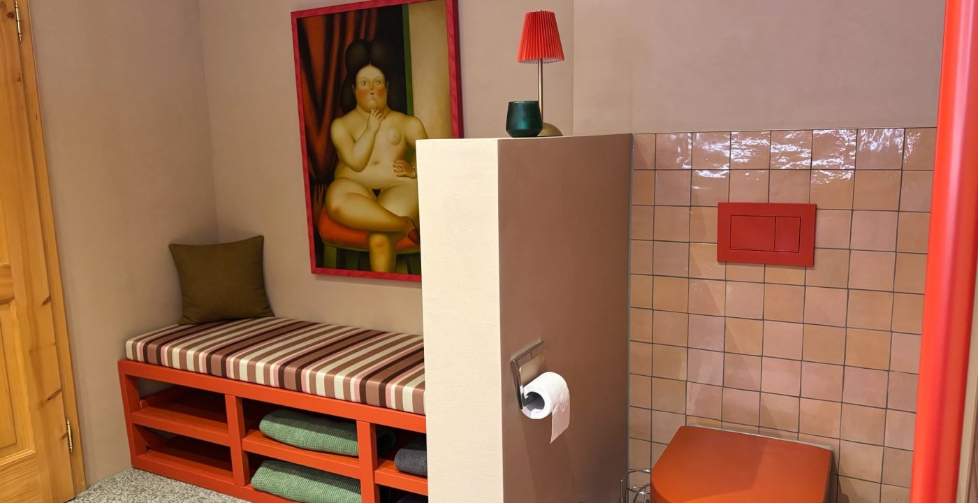 Badkamer in een vakantieappartement met een oranje wc uit de Vitrium-lijn van Duravit en een gestreepte bank in Liberty-stof, door cestsjoukje