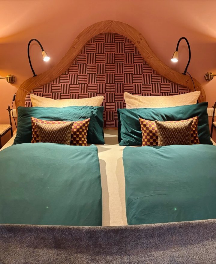 Slaapkamer in een vakantieappartement met houten hoofdbord en wandlampen, door cestsjoukje