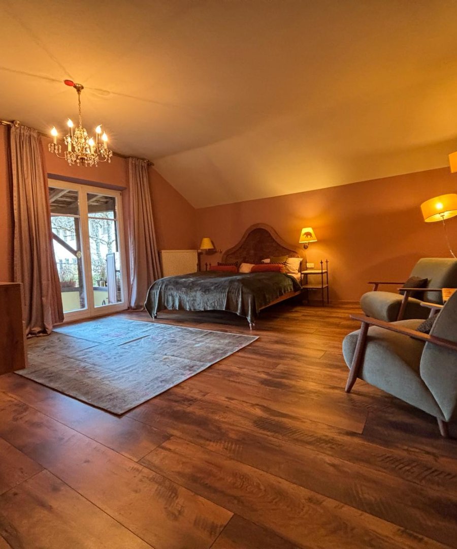 Woonkamer in een vakantieappartement met kroonluchter, houten vloer en warme rosatinten, door cestsjoukje