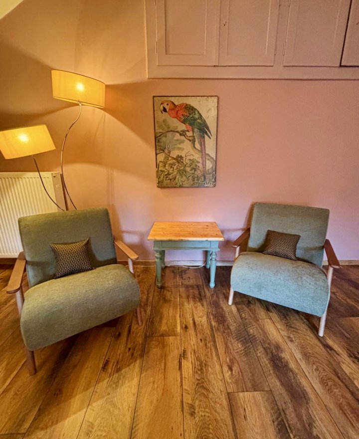 Zithoek in een vakantieappartement met twee groene fauteuils en houten vloer, door cestsjoukje