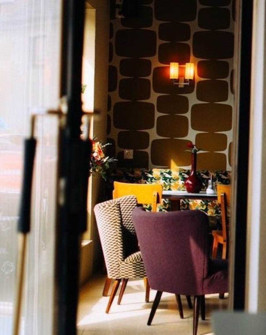 Cafe-interieur met doorkijk, retrobehang en fauteuils, door cestsjoukje