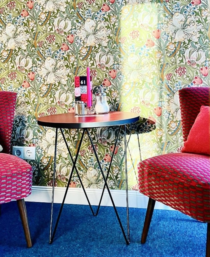 Cafe-interieur met Golden Lily behang van Morris & Co, twee framboosroze vintage fauteuils en een kobaltblauw tapijt, door cestsjoukje