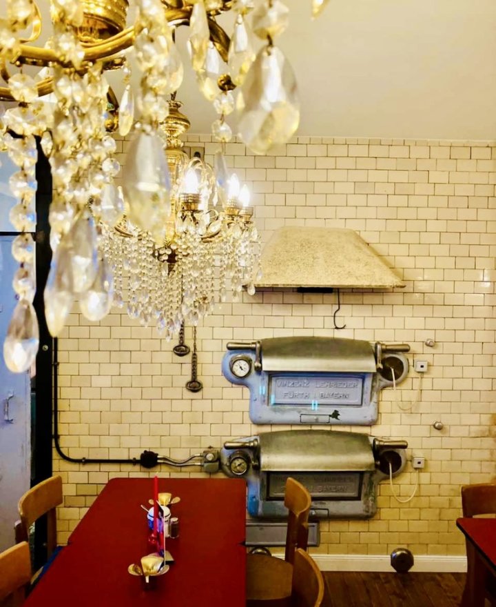 Cafe-interieur met kristallen kroonluchter tegen witte metrotegels, door cestsjoukje