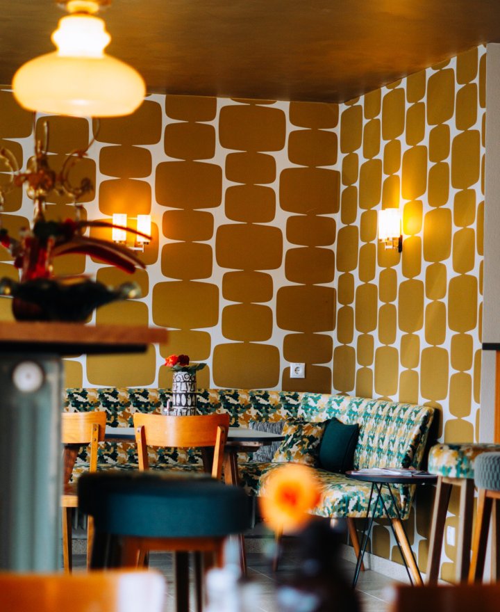 Stadscafe met okergeel retrobehang en een gouden plafond, door cestsjoukje