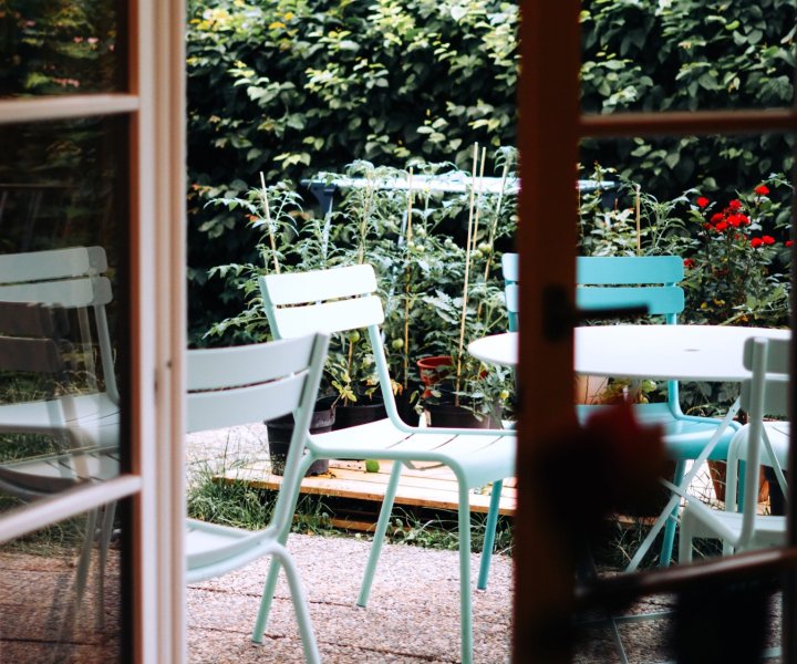 Doorkijk vanuit café Molo Rouge naar het groene terras met mintgroene tuinstoelen en moestuinplanten, door cestsjoukje